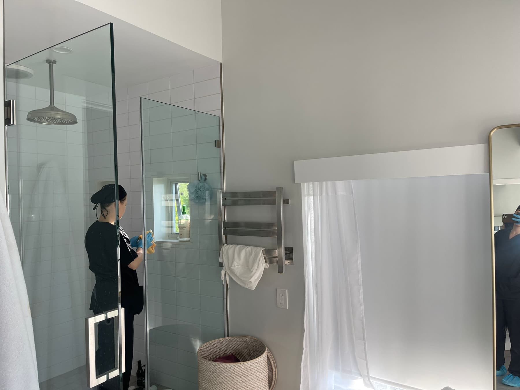 Cleaning a glass shower enclosure in a bright bathroom